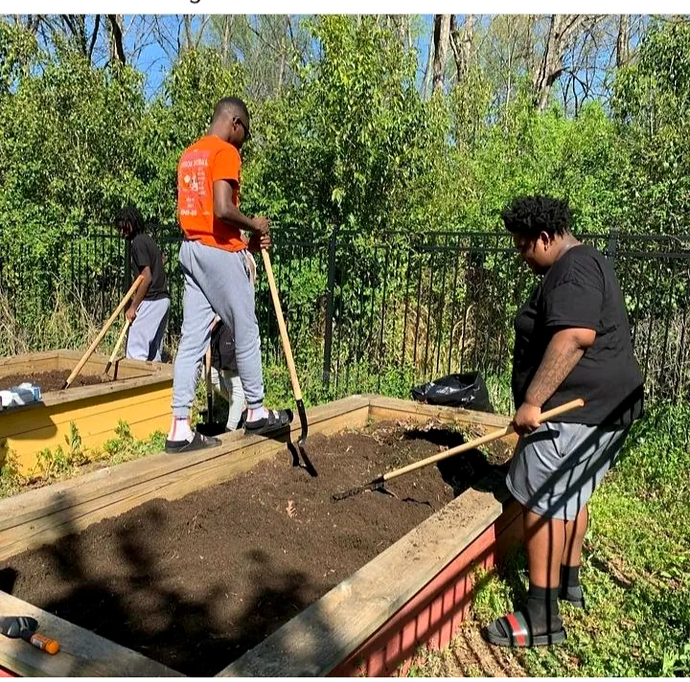 Community members building and turning a raised garden bed together